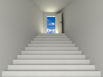 White stairs in a white hall leading to a doorway showing blue skies.